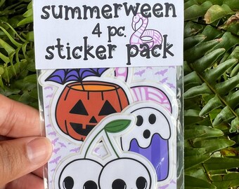 Puede incluir: Un paquete transparente que contiene cuatro pegatinas con temática de Halloween. Las pegatinas incluyen una calabaza, un fantasma y cerezas con caras de calavera. El paquete está etiquetado como "summerween 4 pc. sticker pack".