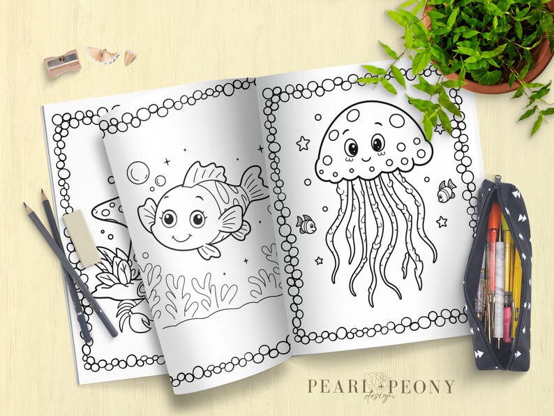 Puede incluir: Libro para colorear abierto con dos p&aacute;ginas con dibujos lineales de un pez y una medusa. El libro est&aacute; rodeado de l&aacute;pices, una goma de borrar, un sacapuntas y un estuche. El libro est&aacute; sobre una superficie de madera clara.
