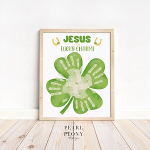 Könnte beinhalten: Ein druckbares Schild mit einem grünen vierblättrigen Kleeblatt mit weißen Handabdrücken. Das Schild lautet "Jesus ist mein Glücksbringer" mit goldenen Hufeisen-Symbolen auf beiden Seiten des Textes.