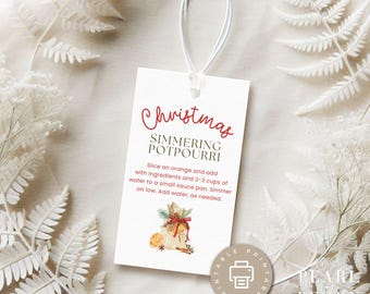 May include: Printable Christmas gift tag with a white background and red text that says "Christmas Simmering Potpourri". The tag features a watercolor illustration of a burlap sack filled with orange slices, cinnamon sticks, and star anise. The text below the illustration reads "Slice an orange and add with ingredients and 2-3 cups of water to a small sauce pan. Simmer on low. Add water, as needed."