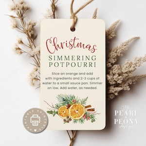 Puede incluir: Etiqueta de receta de potpourri navideño para hervir a fuego lento imprimible con una ilustración de acuarela de rodajas de naranja, palitos de canela, clavos y vegetación. La etiqueta tiene el texto "Potpourri navideño para hervir a fuego lento" e instrucciones para hacer el potpourri.