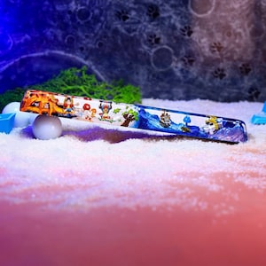 May include: A colorful resin keycap with a blue and white ocean scene and characters from the anime One Piece. The keycap is on a white surface.