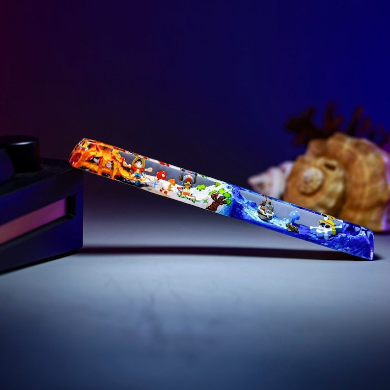 May include: A clear, rectangular, glass-like object with a colorful image of cartoon characters and a ship on a blue ocean. The image is encased in the object, giving it a 3D effect.