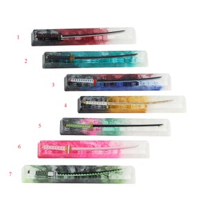 Könnte beinhalten: Sieben verschiedene Tastaturkappen mit einem eingebetteten Schwertdesign. Die Kappen bestehen aus klarem Harz mit verschiedenen Farben und Mustern. Die Schwerter sind alle in verschiedenen Farben und Stilen gehalten.