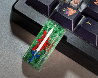 May include: A green, red, and blue keycap with a white sword and a red and white symbol. The keycap is made of resin and has a glittery finish.