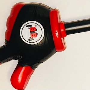 May include: A black and red thumbs up hand shaped stress ball with a black handle. The stress ball has a white circle with the text "BBB" in black letters.