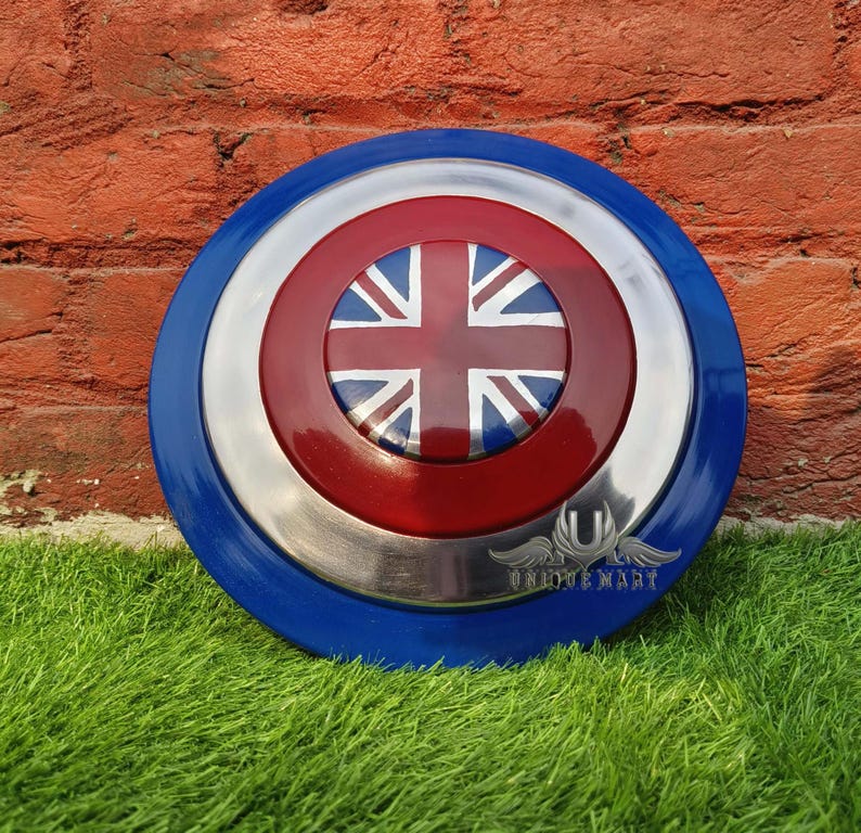 May include: A round, blue and red shield with a silver centre. The shield has a Union Jack flag design in the centre.