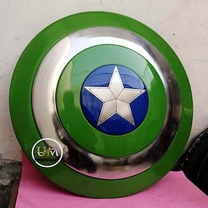 Op de afbeelding: Een groen en zilveren Captain America schild met een blauwe ster in het midden. Het schild is gemaakt van metaal en heeft een verhoogde rand.