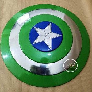 Op de afbeelding: Een groen en zilveren Captain America schild met een blauwe ster in het midden. Het schild is gemaakt van metaal en heeft een glanzende afwerking.
