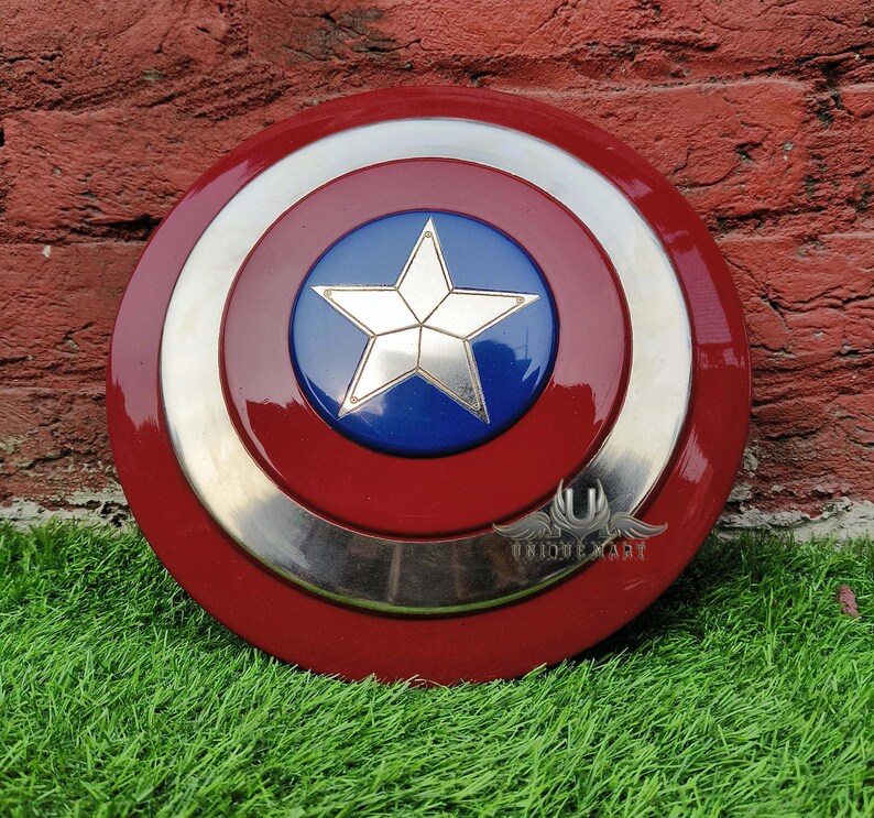 May include: A red, white and blue Captain America shield replica. The shield has a silver metal rim and a blue centre with a white star.
