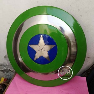 Op de afbeelding: Een groen en zilveren Captain America schild met een blauwe ster in het midden. Het schild is gemaakt van metaal en heeft een verhoogde rand.