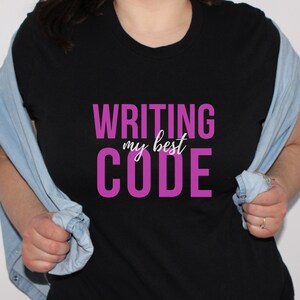 May include: Black t-shirt with the text "WRITING my best CODE" in pink lettering.