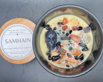May include: Black soy wax candle with a skull, crystals, and a pentagram charm. The candle is labeled "Samhain" and "The Blue Lotus Apothecary".