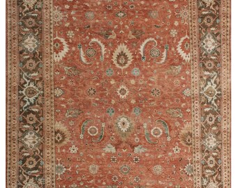 May include: A rectangular area rug featuring a terracotta red field with a central floral medallion and intricate botanical motifs in shades of cream, sage green, and dark brown. The rug is framed by a wide, dark brown border with floral patterns.