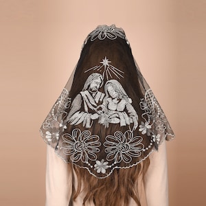 May include: A black lace mantilla with silver embroidery depicting the Holy Family. The embroidery features a star above the figures of Mary, Joseph, and the baby Jesus.