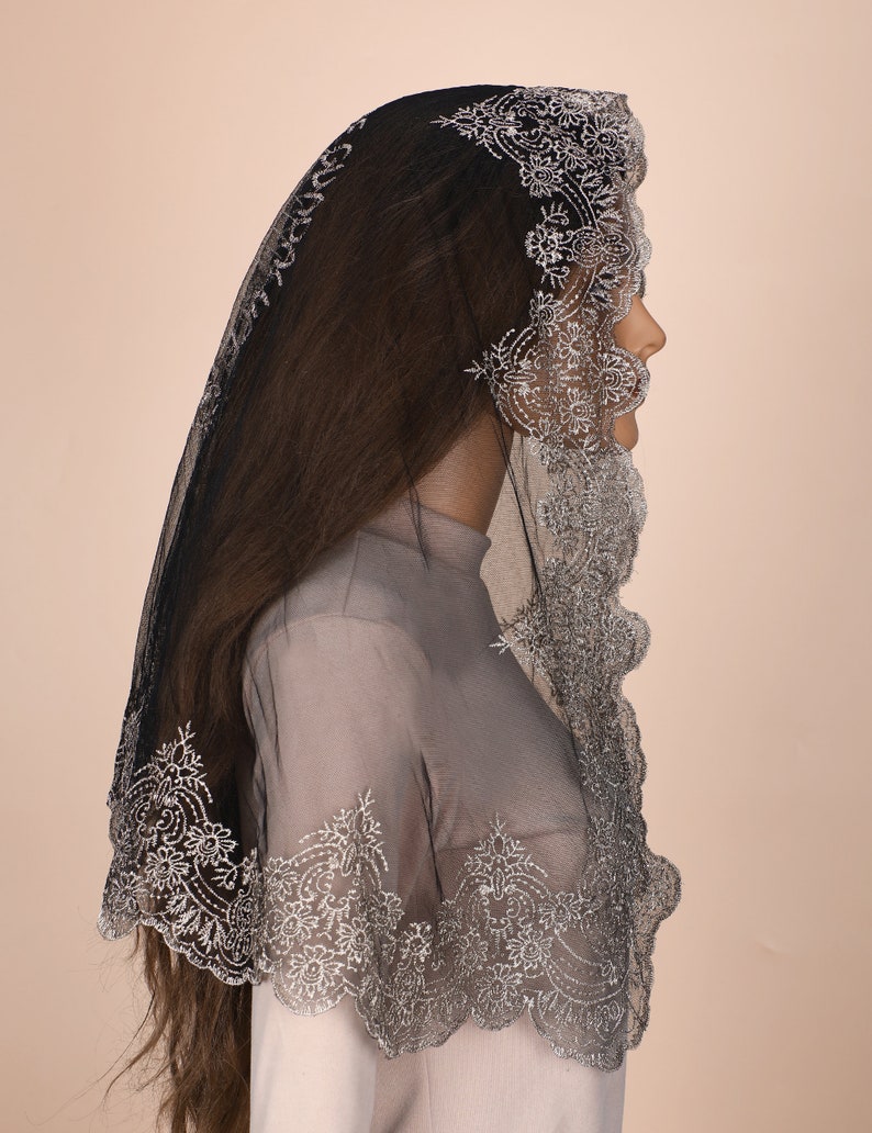 Peut inclure: Une mantille en dentelle noire avec des broderies argent&eacute;es. La dentelle est festonn&eacute;e et pr&eacute;sente un motif floral.