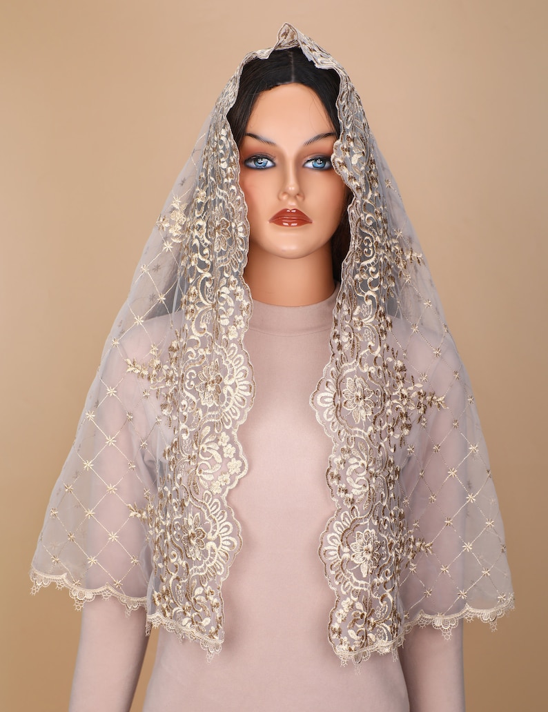 May include: A sheer, light grey veil with gold embroidery. The veil has a scalloped edge and a delicate floral pattern.