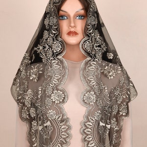May include: A black and gold embroidered veil with a floral design. The veil is made of sheer fabric and features intricate detailing around the edges. The veil is draped over a mannequin.
