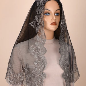 Peut inclure: Mantille en dentelle noire avec des broderies argent&eacute;es. La dentelle a un bord festonn&eacute; et un motif floral.