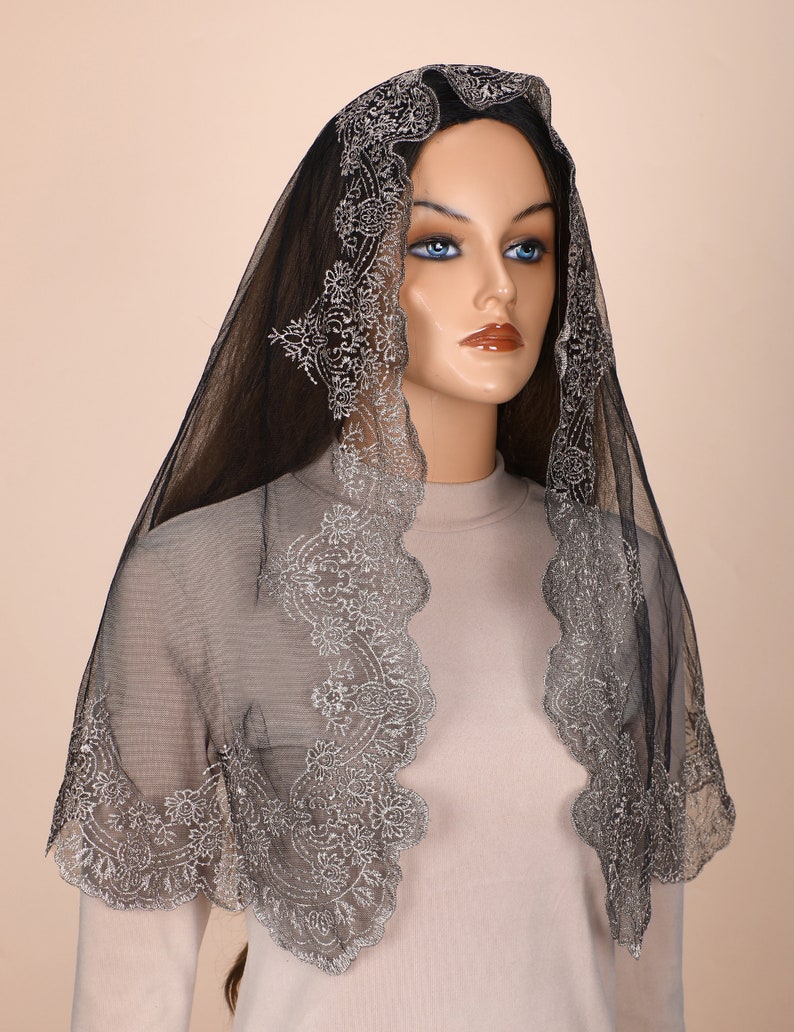 Peut inclure: Mantille en dentelle noire avec des broderies argent&eacute;es. La dentelle a un bord festonn&eacute; et un motif floral.