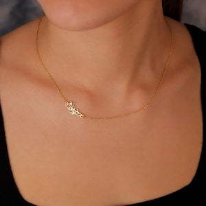 May include: A delicate gold necklace with a small, intricate leaf design pendant.