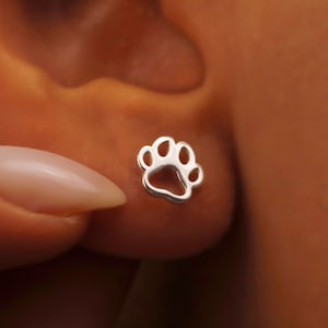 May include: Silver paw print stud earrings. The earrings are small and delicate, and they are perfect for anyone who loves dogs or cats.