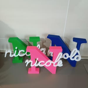 Puede incluir: Una taza de cerámica blanca con un asa negra y el texto "But First, Coffee" en negrita negra. La taza se encuentra sobre un fondo borroso, resaltando su diseño sencillo.