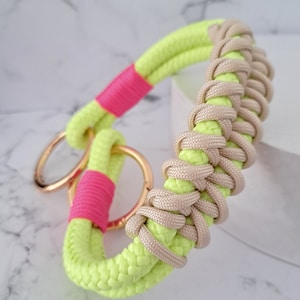 Könnte beinhalten: Ein limegrünes und pinkfarbenes geflochtenes Hundekollier mit goldfarbener Metallbeschläge.