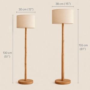 May include: Two wooden floor lamps. The smaller lamp is 51 inches tall with a 12-inch lampshade. The larger lamp is 61 inches tall with a 15-inch lampshade. Both lamps have a natural wood finish and beige fabric shades.