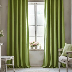 May include: Lime green striped curtains frame a window, with a white chair and a small table in the foreground. The curtains are the focal point, adding a vibrant touch to the room. A small white table and chair are in the foreground.