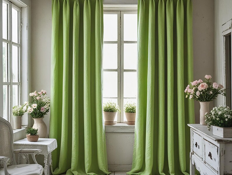 May include: Bright green linen curtains hang in front of a window, framing the view. The curtains are floor-length and have a textured appearance. The room is decorated with white furniture and vases of flowers, creating a fresh and airy atmosphere.