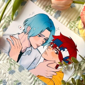 May include: A rectangular art print featuring a digital illustration of two anime-style characters. One character has light blue hair and a white shirt, while the other has red hair, a blue headband, and a yellow shirt. The characters are close together.