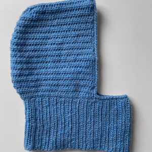 Puede incluir: Una balaclava de punto azul con una sola abertura para los ojos.