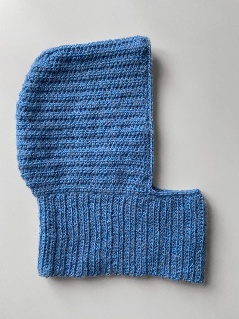 Puede incluir: Una balaclava de punto azul con una sola abertura para los ojos.