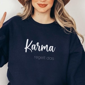 May include: A navy blue sweatshirt with white text that reads "Karma regelt das".