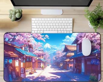 May include: A rectangular mousepad featuring a Japanese village scene with cherry blossoms, traditional buildings, and a snow-capped mountain under a blue sky. A white mouse and keyboard are on the wooden desk.