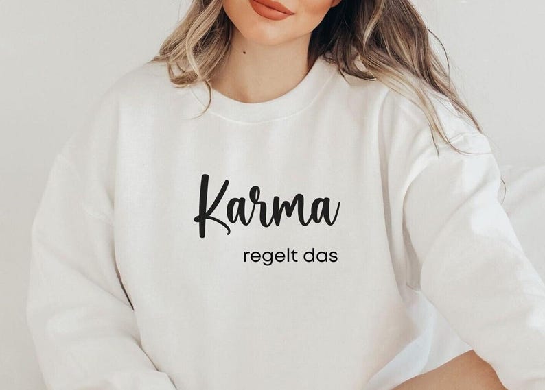 May include: White sweatshirt with the text "Karma regelt das" in black lettering.