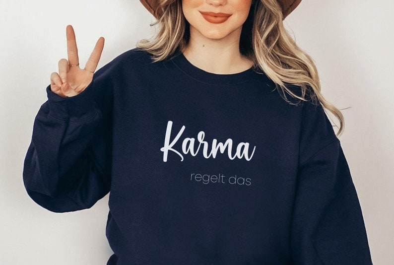May include: A navy blue sweatshirt with white text that reads "Karma regelt das".