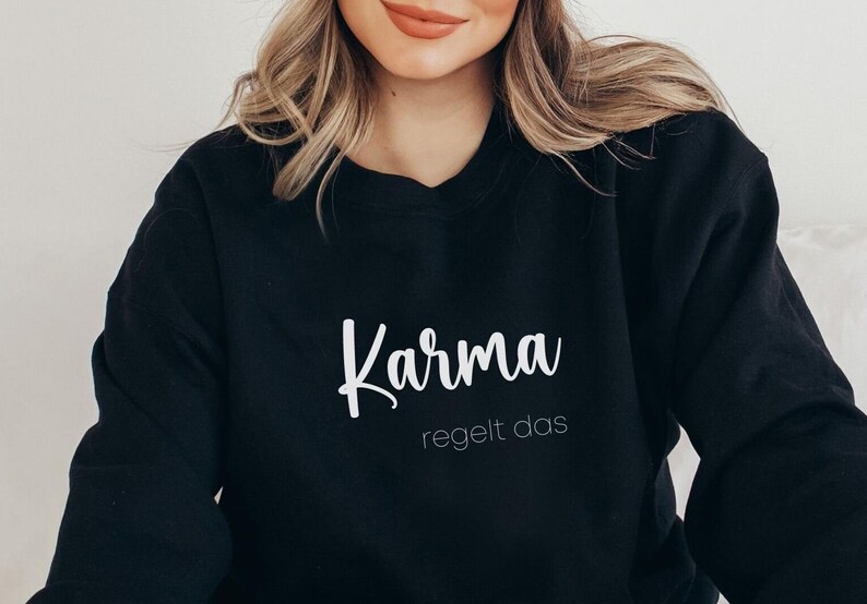 May include: Black sweatshirt with white text that reads "Karma regelt das".
