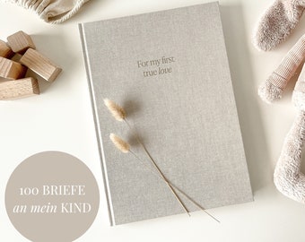 Può includere: Un diario beige rivestito in lino con il testo "For my first true love" sulla copertina. Il diario è circondato da oggetti decorativi, tra cui erbe secche, blocchi di legno e un coniglietto di peluche. Il testo "100 Briefe an mein Kind" è visibile nell'angolo in basso a sinistra dell'immagine.