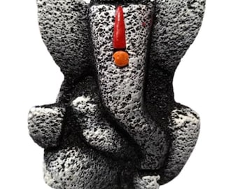 Op de afbeelding: Gedetailleerd beeld van de hindoeïstische godheid Ganesha, afgebeeld in zittende positie. De sculptuur is voornamelijk zwart-wit met een getextureerd uiterlijk. Een rode en oranje markering siert het voorhoofd en voegt kleur toe.