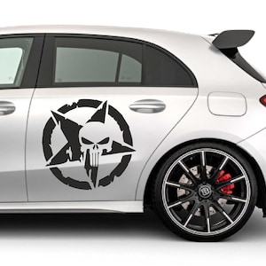 Könnte beinhalten: Ein schwarz-weißer Aufkleber mit einem Schädel- und Stern-Design ist an der Seite eines silbernen Autos angebracht. Der Schädel befindet sich in einem Stern und einem kreisförmigen Rahmen, was eine auffällige Grafik ergibt.