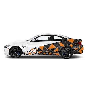 Può includere: Auto sportiva bianca con design geometrico nero e arancione sul lato e sul retro. L'auto ha ruote nere con pinze freno blu. Il design presenta triangoli e linee.
