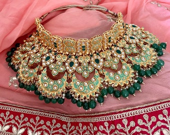 May include: A gold and green statement necklace with a layered design featuring crescent moon shapes, intricate floral patterns, and green gemstones. The necklace is adorned with pearls and is perfect for a special occasion.
