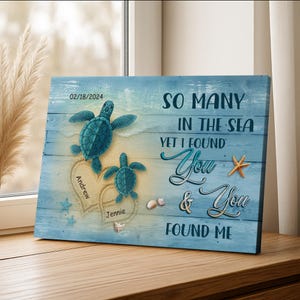 May include: A blue wooden wall art piece featuring two teal sea turtles above two heart-shaped sand designs. The text reads "So Many in the Sea, Yet I Found You & You Found Me." Names "Andrew" and "Jennie" are included.
