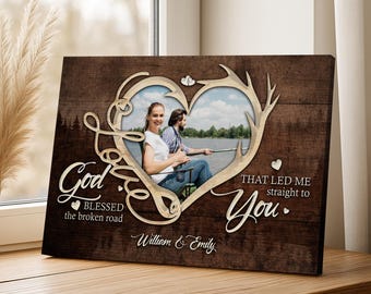 May include: A wooden framed canvas print featuring a couple in a heart-shaped frame with deer antlers. The text reads "God blessed the broken road that led me straight to you." The names "William & Emily" are also displayed.