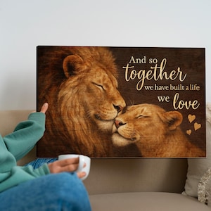 May include: A wood-grain background with a lion and lioness cuddling. The text reads "And so together we have built a life we love" with gold hearts.