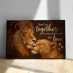 May include: A wood-grain background with a couple of lions cuddling. The text reads "And so together we have built a life we love" with gold hearts.