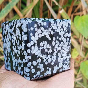 May include: A black and white snowflake obsidian cube with a polished finish. The cube has a unique pattern of white snowflake-like inclusions.