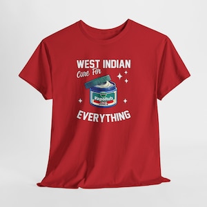 Puede incluir: Camiseta roja con el texto "WEST INDIAN Cure For EVERYTHING". La camiseta presenta un gráfico de un frasco de VapoRub con tapa verde y crema blanca. El frasco de VapoRub tiene una etiqueta azul con el nombre de la marca.